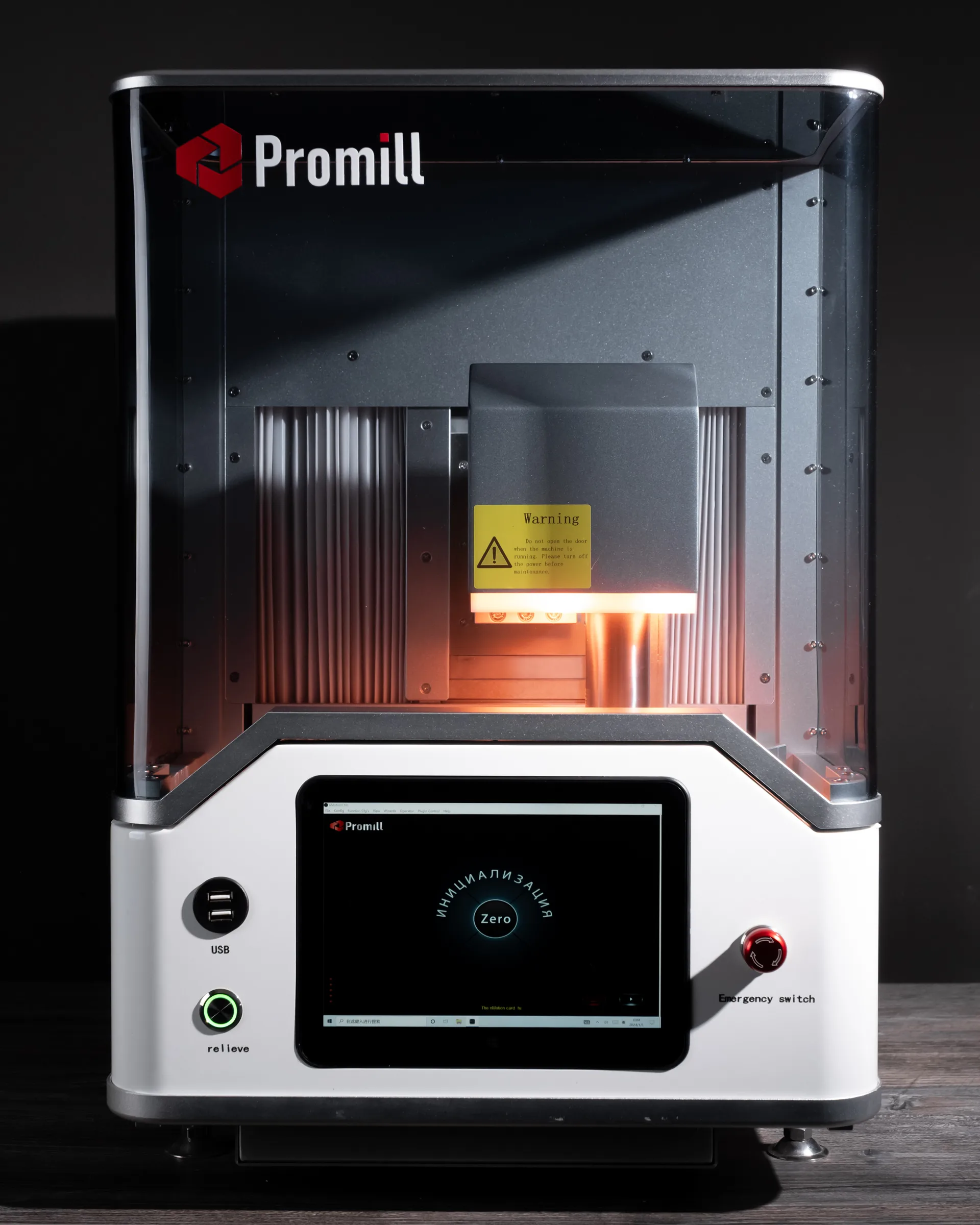 3D-принтер Promill с открытой камерой печати, оранжевым нагревательным элементом и жёлтым предупреждающим ярлыком, сенсорный дисплей на белой базе показывает интерфейс калибровки