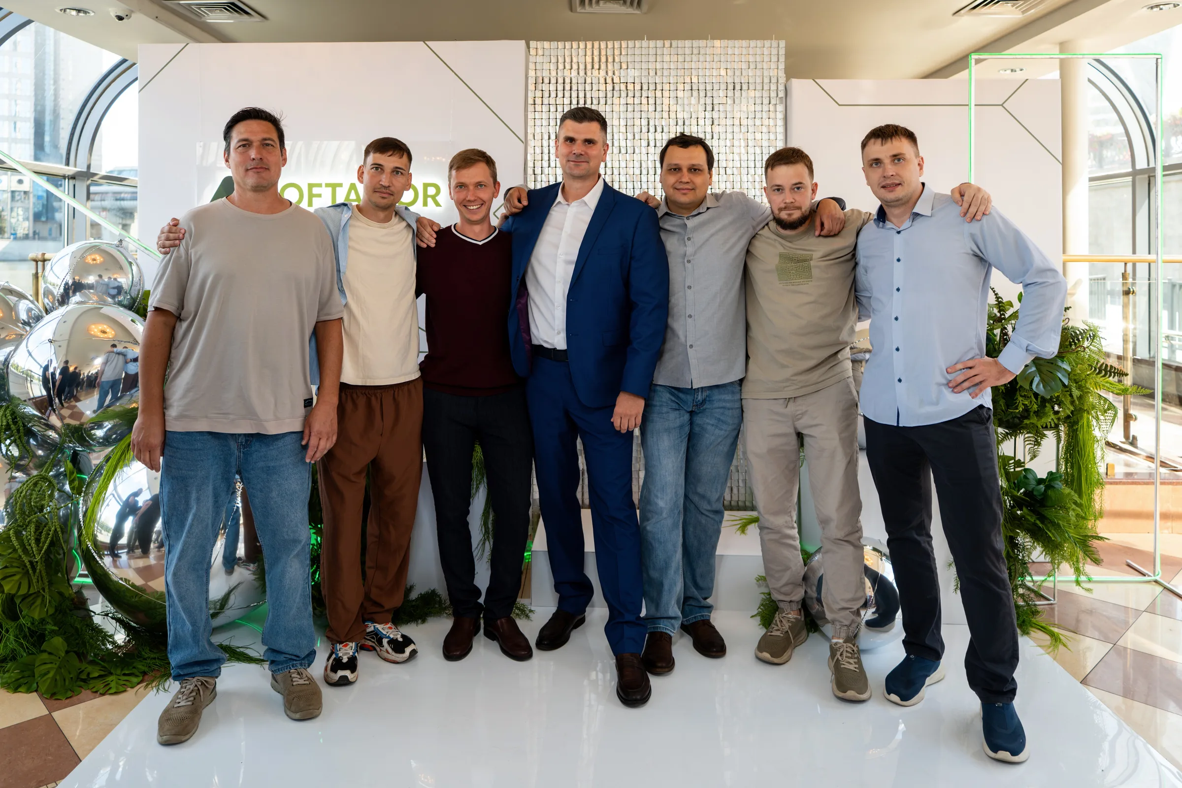 Семеро мужчин обнялись у фотозоны с логотипом компании и надписью «10 лет» в зале теплохода